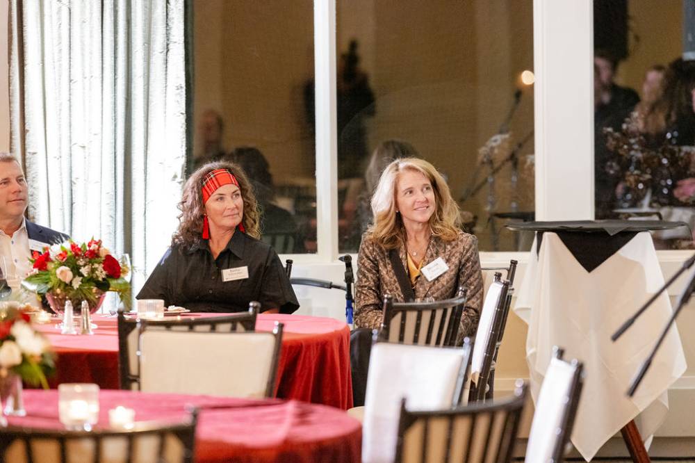 Two woman at reception smiling and looking up at speaker